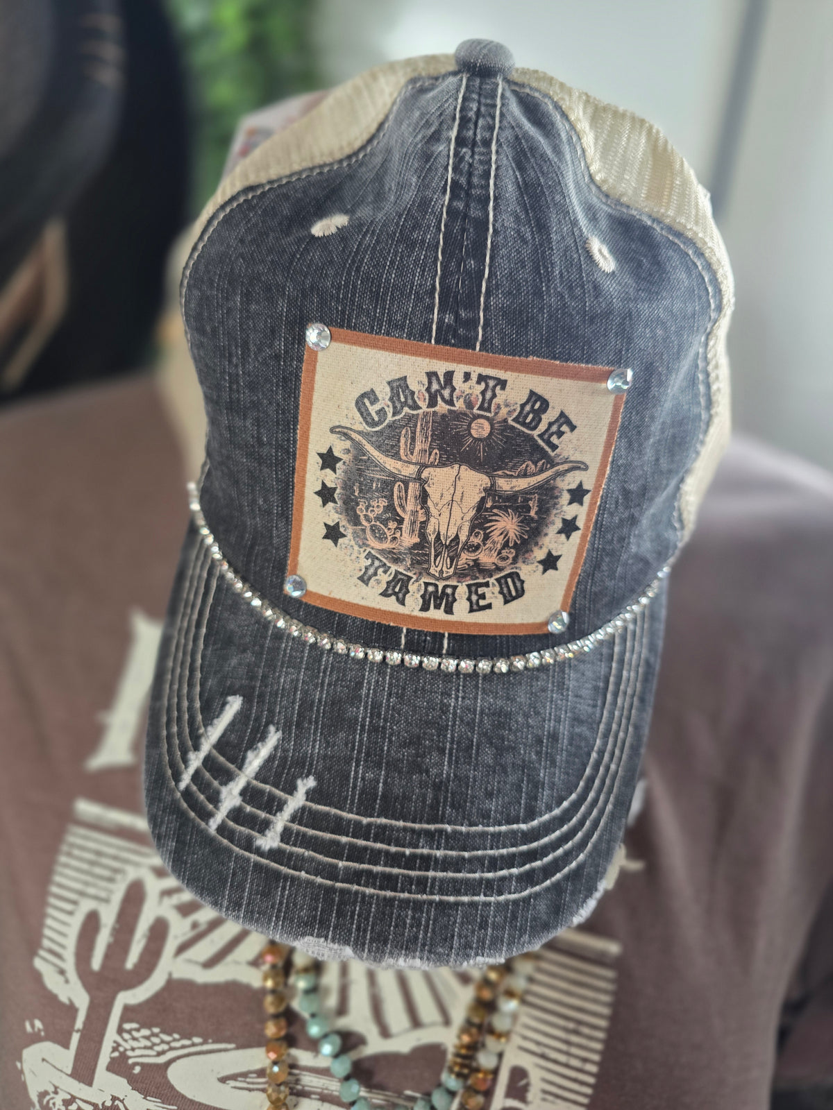 "CAN'T BE TAMED" DISTRESSED TRUCKER HAT: BLING/  BLACK KHAKI
